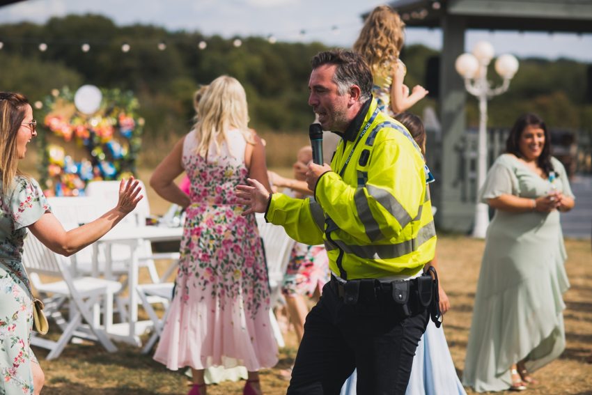 Matthew performing as a police character among guests at an outdoor celebration